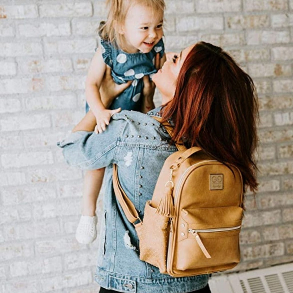 Chelsea + Cole for Itzy Ritzy Mini Diaper Bag Backpack - Studded Mini Diaper Bag Backpack with Changing Pad, 8 Pockets, Rubber Feet & Tassel Caramel